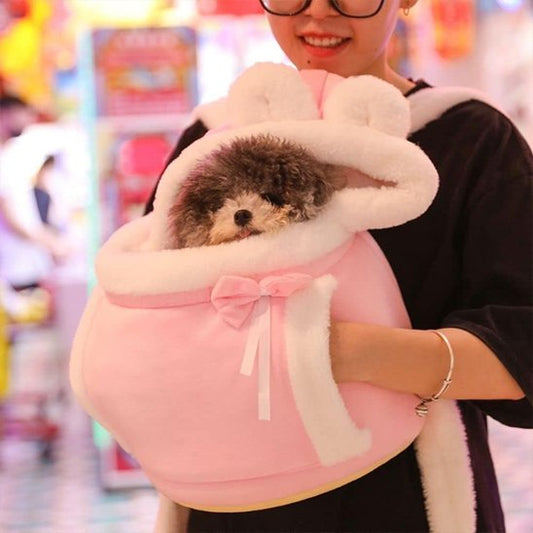 Sac de transport chien rose porté par femme sur ventre avec main dans poche sur coté